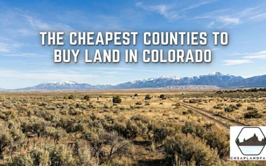 Wide panoramic view of cheap raw land for sale in Alamosa County Colorado with dirt road leading toward the Great Sand Dunes and snow-capped Sangre de Cristo Mountains under a blue sky.
